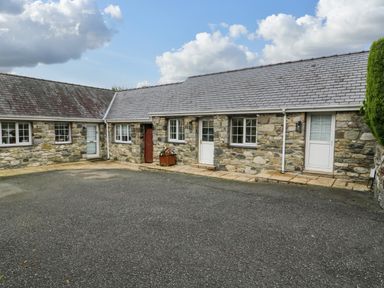 A stone exterior building with multiple white doors and windows under a slate roof at Bwythyn Yr Wyddfa in Llanberis