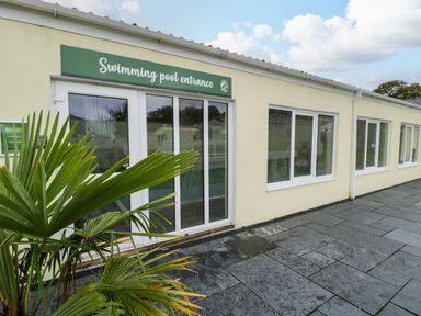 Entrance to a swimming pool with sliding glass doors and a green sign above at Bwythyn Yr Wyddfa in Llanberis