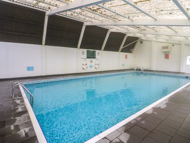 An indoor swimming pool with a tiled floor and life rings on the wall at Bwythyn Yr Wyddfa in Llanberis