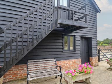 An exterior view with stairs, bench and flowers at The Cow Shed in Chediston near Halesworth