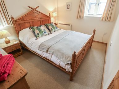 A bedroom with a wooden bed and bedside table at The Cow Shed in Chediston near Halesworth