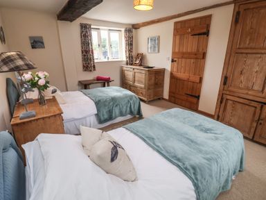 A bedroom with two beds and wooden furniture at The Cow Shed in Chediston near Halesworth