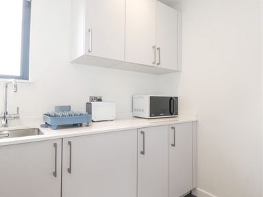 A kitchen counter with a sink dish rack toaster and microwave at Bluebell Cabin Ullswater