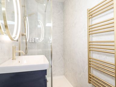 A bathroom with a sink mirror shower and gold towel rack at Bluebell Cabin in Ullswater
