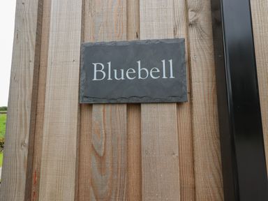 A slate nameplate with Bluebell text mounted on a wooden wall at Bluebell Cabin in Ullswater