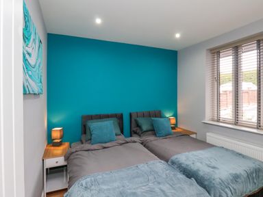 A bedroom with two single beds against a teal accent wall at The Dollhouse in Cayton Bay