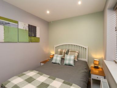 A bedroom with a double bed and bedside tables with lamps at The Dollhouse in Cayton Bay