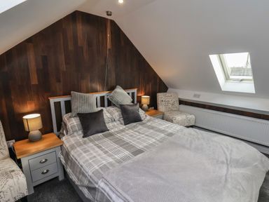 A bedroom with a double bed bedside tables with lamps a chair and a skylight window at The Dollhouse in Cayton Bay