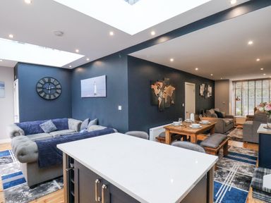 An open living and dining area with sofas tables and wall art at The Dollhouse in Cayton Bay