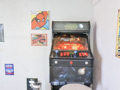 A Star Wars arcade game machine and various decorative posters on a white wall at The Dollhouse in Cayton Bay
