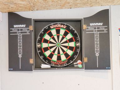 A dartboard with two scoreboards and darts at The Dollhouse in Cayton Bay