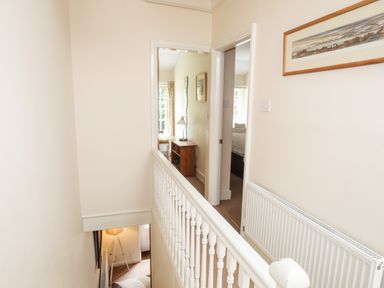 A hallway with two doorways and a wooden console table with a lamp visible at Ty Nain in Beddgelert