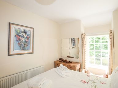 A bedroom with a bed towel arrangement a wooden desk a mirror and a window at Ty Nain in Beddgelert