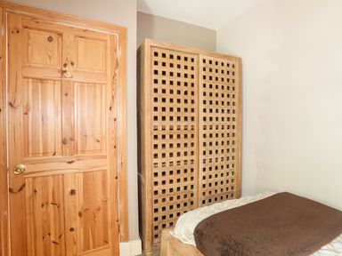A bedroom with a wooden door a wooden wardrobe and a bed with a brown blanket at Ty Nain in Beddgelert