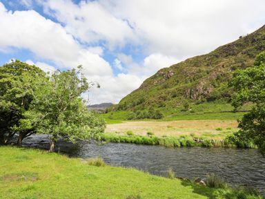 A river with trees on the bank and a hill in the background at Ty Nain in Beddgelert