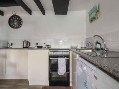 A kitchen with a stove kettle microwave washing machine and sink at Chy Rani in Portmellon near Mevagissey