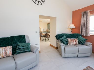A living room with sofas and a doorway leading to the dining area at Y Stabal near Llanilar