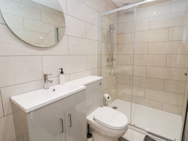 A bathroom with a shower, toilet, sink, and mirror at Y Stabal near Llanilar