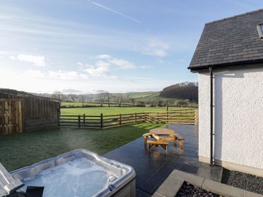 A garden with a hot tub and an outdoor seating area at Beudy near Llanilar