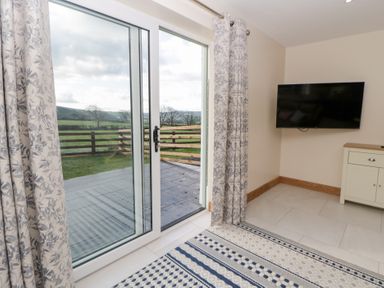 A living room with a sliding door and television at Beudy near Llanilar