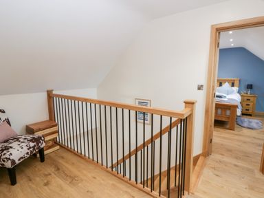 A hallway with a staircase and access to a bedroom at Beudy near Llanilar