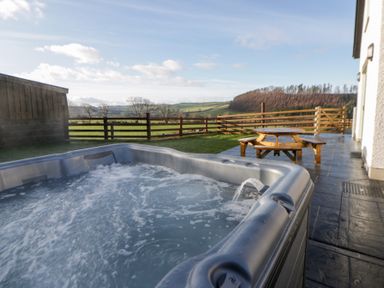 An outdoor area with a hot tub and wooden table at Beudy near Llanilar
