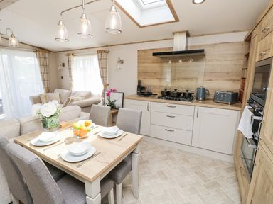 A kitchen and dining area with table set for four and beige sofas in the background at 7 Wild Haven in Landford