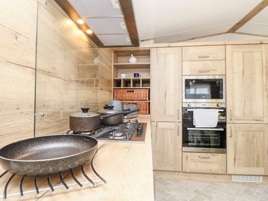 A kitchen with wooden cabinets stovetop with pots and a frying pan oven and microwave at 7 Wild Haven in Landford