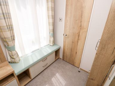A small room with a window seat cushion storage drawers wooden door and carpeted floor at 7 Wild Haven in Landford