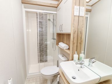 A bathroom with a shower, toilet, sink, and storage cabinets at 7 Wild Haven in Landford