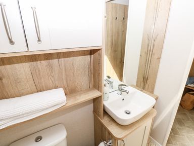 A bathroom with a sink a mirror a cabinet a toilet and folded towels at 7 Wild Haven in Landford