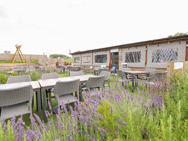 An outdoor seating area with tables and chairs next to a building and a playground at 7 Wild Haven in Landford