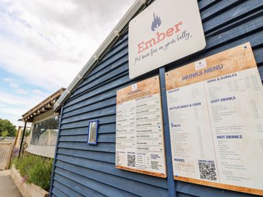 A blue wooden building with Ember restaurant food and drinks menus displayed outside at 7 Wild Haven in Landford
