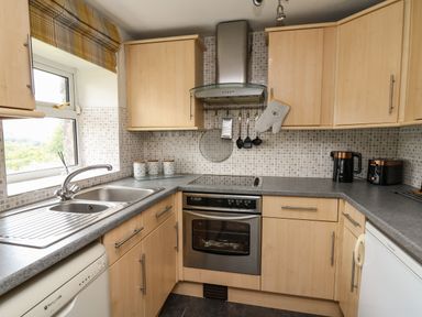 A kitchen with a sink, stove, oven, cabinets, and small appliances at Yewtree Cottage in Defynog near Sennybridge