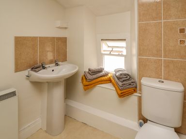 A bathroom with a sink a toilet and towels on a windowsill at Yewtree Cottage in Defynog near Sennybridge