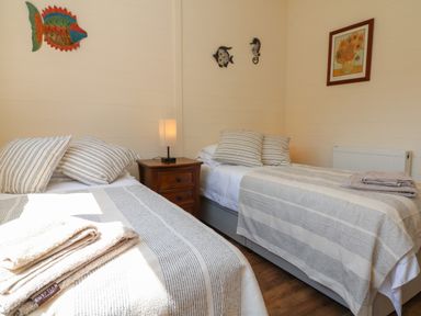 A bedroom with two single beds bedside table with lamp and wall decorations at At the Bay Apartment in Hele Bay Ilfracombe