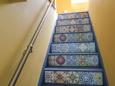 A staircase with patterned tiles on the risers and yellow walls at At the Bay Apartment in Hele Bay Ilfracombe