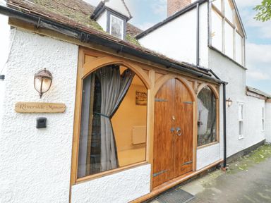 The entrance of a building with wooden double doors and arched windows with curtains at Riverside Manor in Evesham