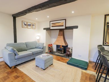 A living room with a blue sofa and ottoman near a fireplace with a wooden floor at Riverside Manor in Evesham