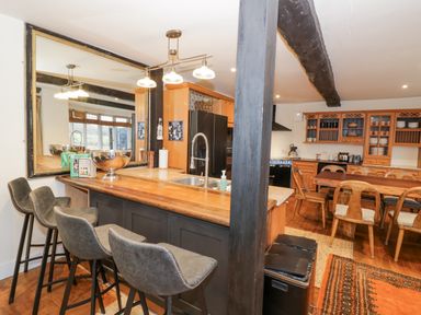 A kitchen with bar stools a wooden dining table and chairs and wooden cabinetry at Riverside Manor in Evesham