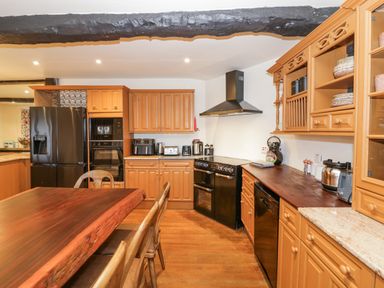 A kitchen with wooden cabinets black appliances and a dark wooden dining table at Riverside Manor in Evesham