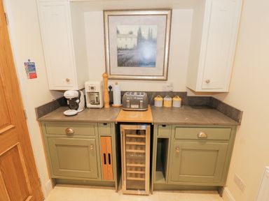 A kitchen counter with green cabinets a toaster coffee machine and canisters at Riverside Manor in Evesham