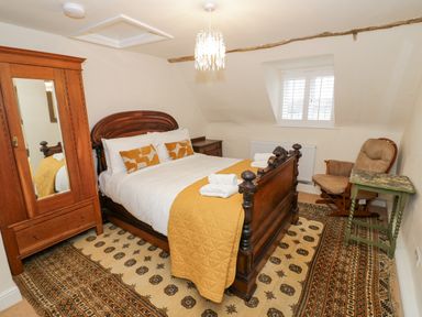 A bedroom with a wooden bed and wardrobe a chair and side table with a window at Riverside Manor in Evesham