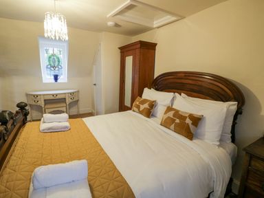 A bedroom with a large bed wooden headboard white pillows and a quilt at Riverside Manor in Evesham