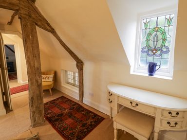A hallway with a wooden beam and a small rug near a white desk under a stained glass window at Riverside Manor in Evesham