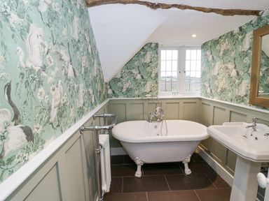 A bathroom with a clawfoot bathtub a pedestal sink and bird patterned wallpaper at Riverside Manor in Evesham
