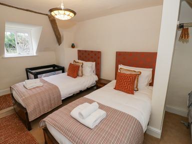 A bedroom with two single beds and a baby cot at Riverside Manor in Evesham