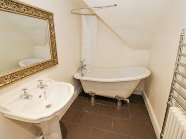 A bathroom with a pedestal sink mirror clawfoot bathtub and heated towel rack at Riverside Manor in Evesham