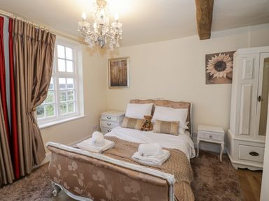 A bedroom with a bed sets with pillows and towels bedside tables curtains and a wardrobe at Riverside Manor in Evesham