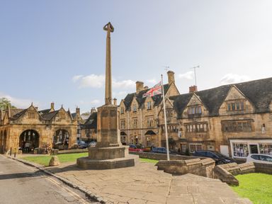 A stone monument with a flagpole and old stone buildings in the background at Riverside Manor in Evesham